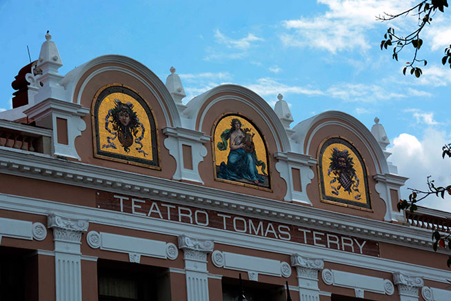 El teatro Tomás Terry luce, en lo más alto de su fachada principal, tres mosaicos teselados con las máscaras coloreadas de las musas: de la comedia (D), la música (C) y la tragedia (I), ubicadas en este orden, es uno de los más elegantes edificios eclécticos de la ciudad de Cienfuegos, Cuba, el 18 de abril del 2019. El teatro Tomás Terry luce, en lo más alto de su fachada principal, tres mosaicos teselados con las máscaras coloreadas de las musas: de la comedia (D), la música (C) y la tragedia (I), ubicadas en este orden, es uno de los más elegantes edificios eclécticos de la ciudad de Cienfuegos, Cuba, el 18 de abril del 2019.