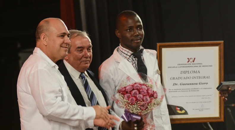 El Dr. Roberto Morales Ojeda (I), vicepresidente de los Consejos de Estado y de Ministros, y el Dr. Antonio López Gutiérrez (C), Rector de la Escuela Latinoamericana de Medicina (ELAM), entregan el Titulo de Medicina y el Diploma de Reconocimiento a egresados de la XV Graduación de la ELAM, en el Teatro Karl Marx, en La Habana, el 23 de julio de 2019.