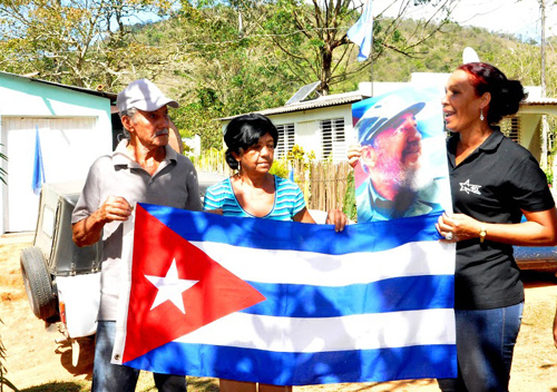 Olivia González Jerez entrega la bandera cubana como reconocimiento a pobladores destacados en la comunidad Cirugía, Buey Arriba, Granma. Foto: ACN