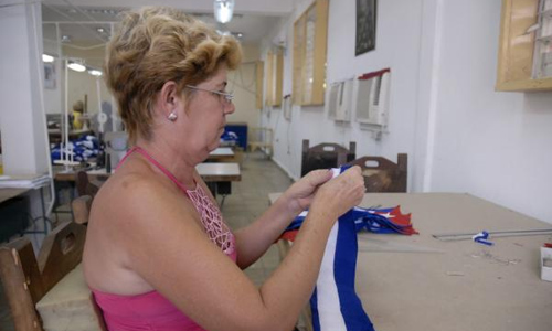 Trabajadora de la fábrica de la Fábrica de Banderas de la Unidad de Medios de Propaganda del Comité Provincial del Partido, en Pinar del Río, comprueba las medidas de las confeccionadas en pequeño formato, el 30 de septiembre de 2015. AIN FOTO/Evelyn CORBILLÓN DÍAZ