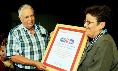 Edda Diz Garcés (D), directora de la Agencia de Información Nacional (AIN),recibe un reconocimiento de manos de Alfonso Bórges, jefe del Departamento Ideológico del Comité Central del Partido, durante el acto político cultural por el Aniversario 40 de la AIN, realizado en el Memorial 